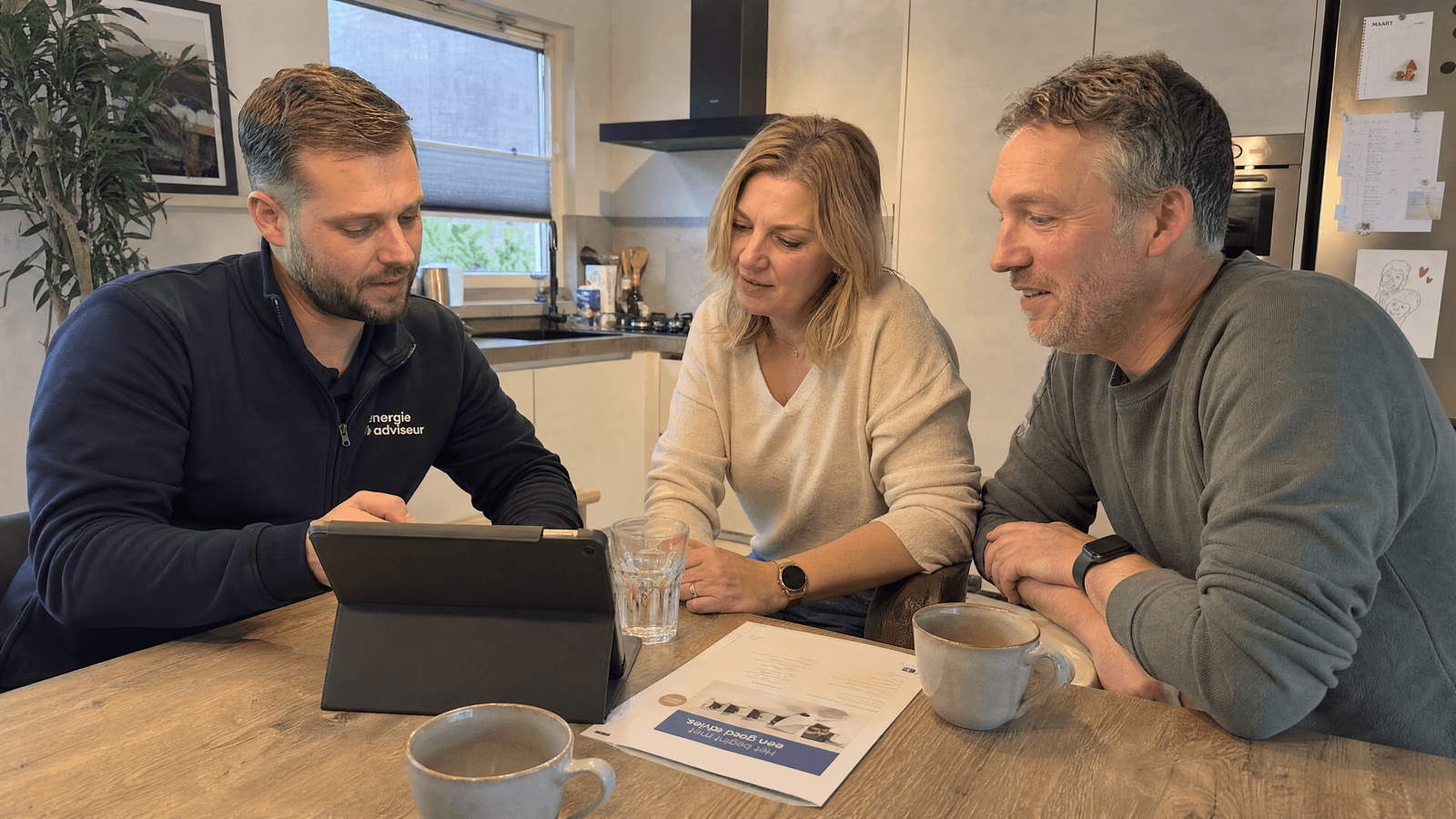 Een adviseur bespreekt de verduurzaming met een echtpaar aan de keukentafel