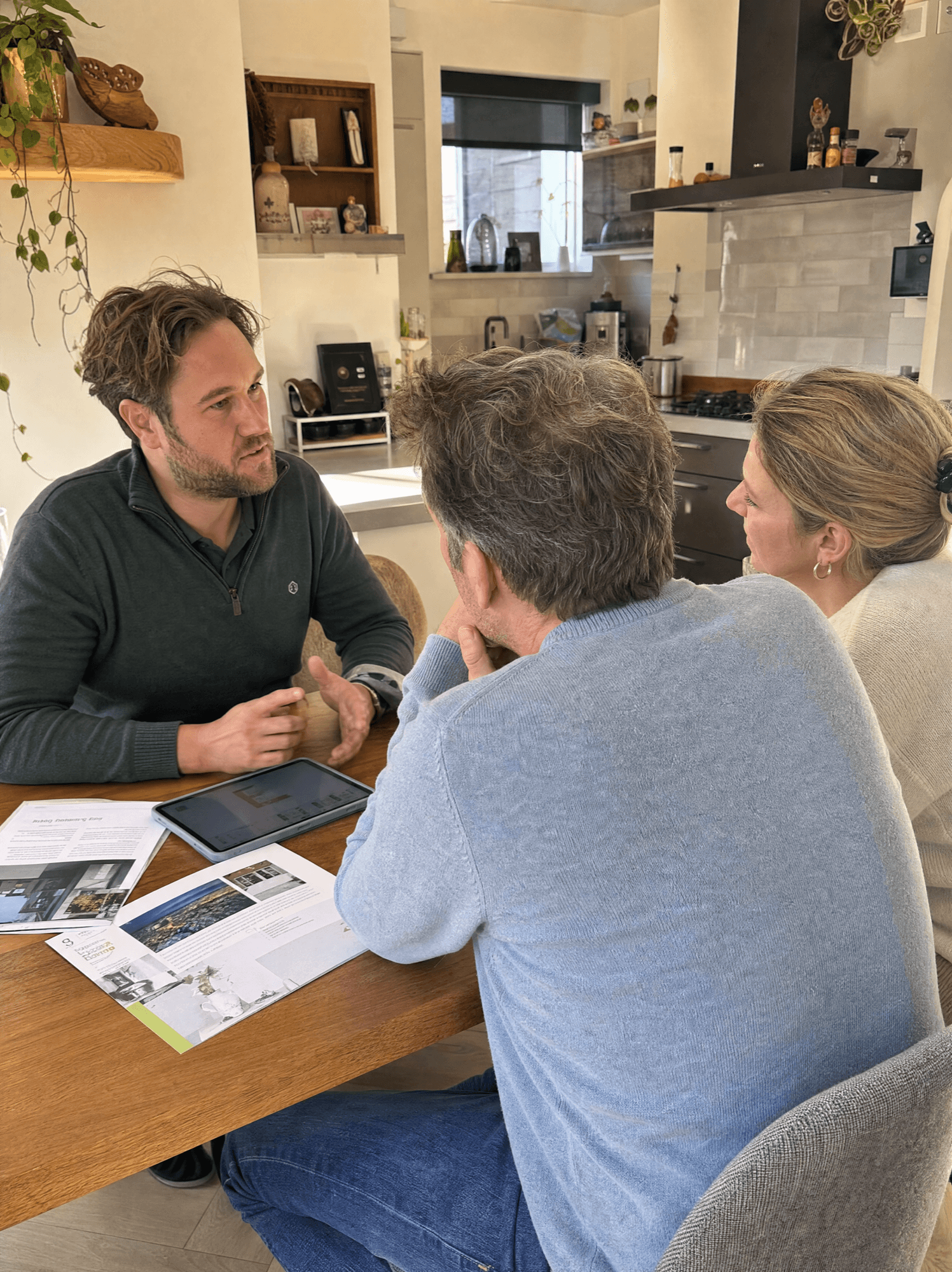 Een lokale adviseur bespreekt de verduurzaming met een echtpaar aan de keukentafel